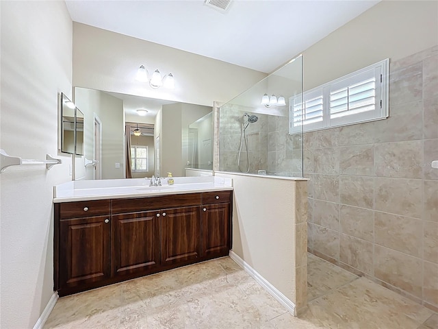 full bathroom with baseboards, ceiling fan, vanity, and walk in shower