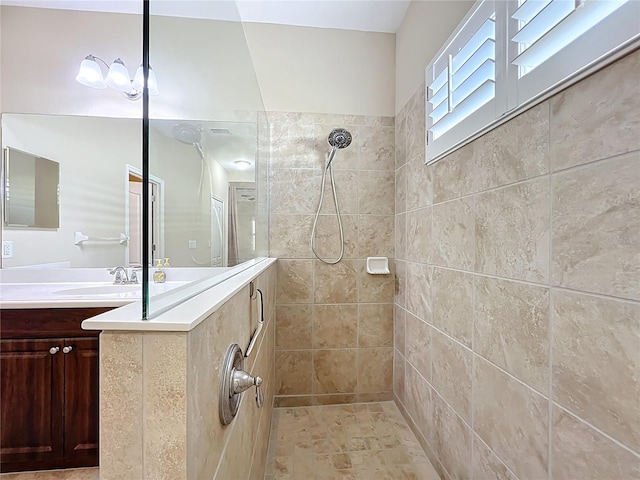 full bathroom with tiled shower and vanity