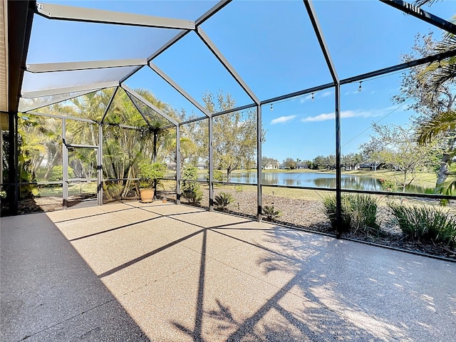 view of patio with glass enclosure and a water view