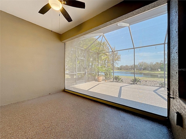 unfurnished sunroom featuring ceiling fan and a water view