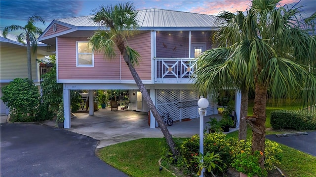 beach home with aphalt driveway, a carport, metal roof, and stairs