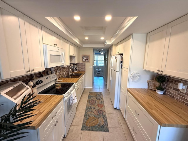 kitchen featuring a sink, white appliances, a raised ceiling, and butcher block counters