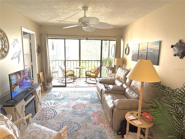 living area with a glass covered fireplace, a textured ceiling, and a ceiling fan