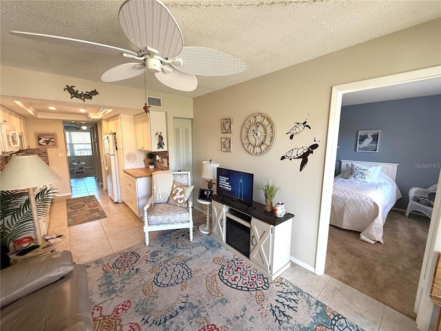 living room with visible vents, baseboards, light tile patterned flooring, a textured ceiling, and a ceiling fan