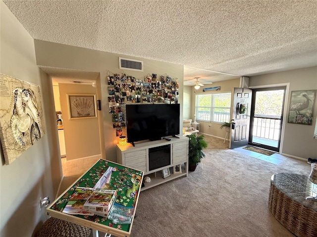 carpeted living room featuring visible vents, baseboards, a textured ceiling, and ceiling fan