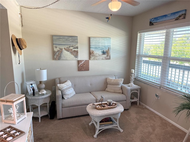 carpeted living area with ceiling fan and baseboards