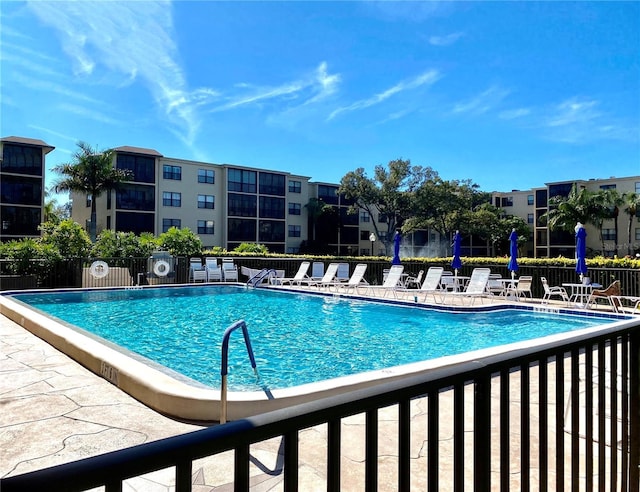 community pool with a patio and fence