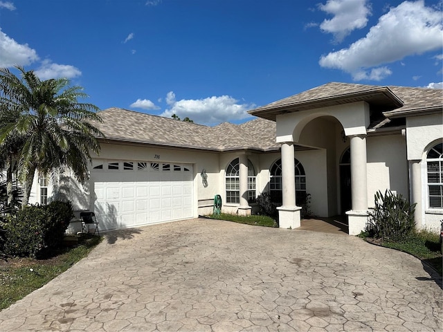 view of front of property featuring decorative driveway, an attached garage, and stucco siding