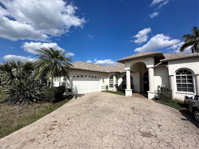 view of front facade featuring stucco siding, driveway, and a garage