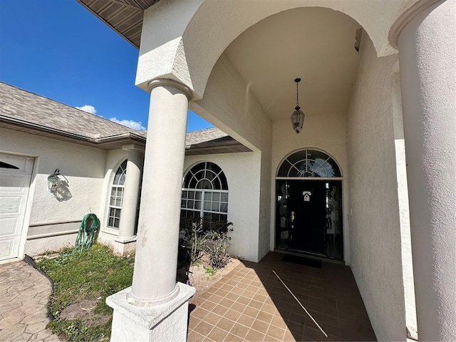 entrance to property with stucco siding and a shingled roof