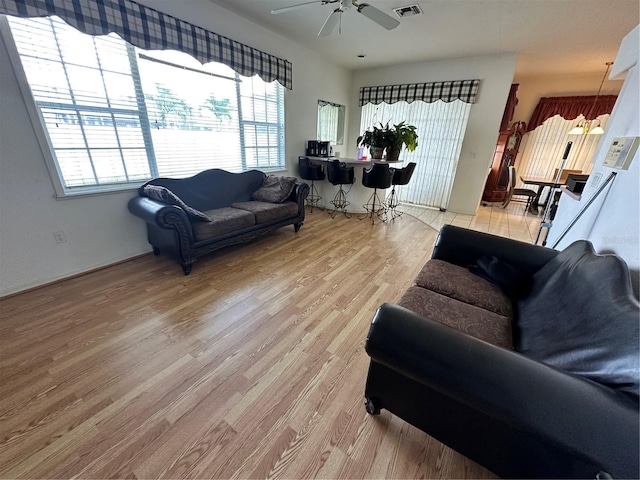 living room featuring visible vents, a ceiling fan, and light wood finished floors