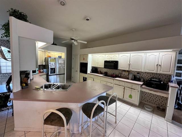 kitchen featuring backsplash, black microwave, light tile patterned floors, a peninsula, and stainless steel refrigerator with ice dispenser