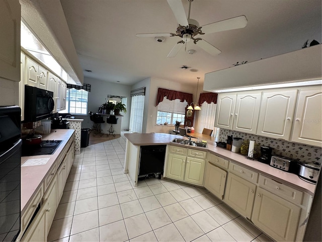 kitchen featuring a peninsula, a sink, black appliances, light countertops, and tasteful backsplash