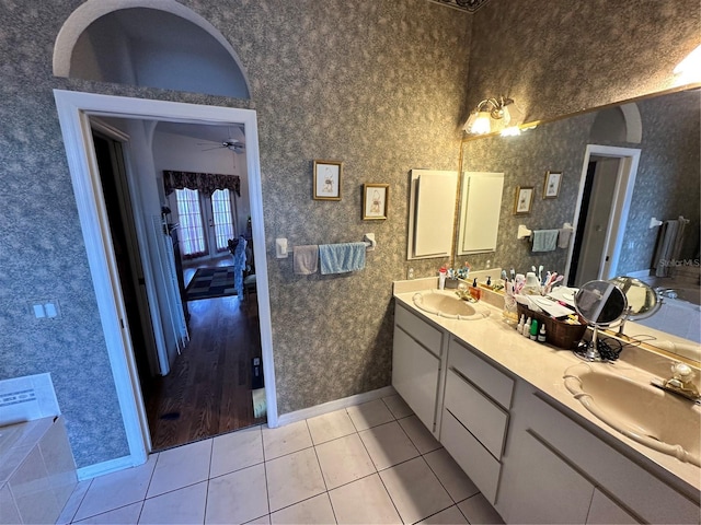 full bath featuring tile patterned flooring, double vanity, wallpapered walls, and a sink