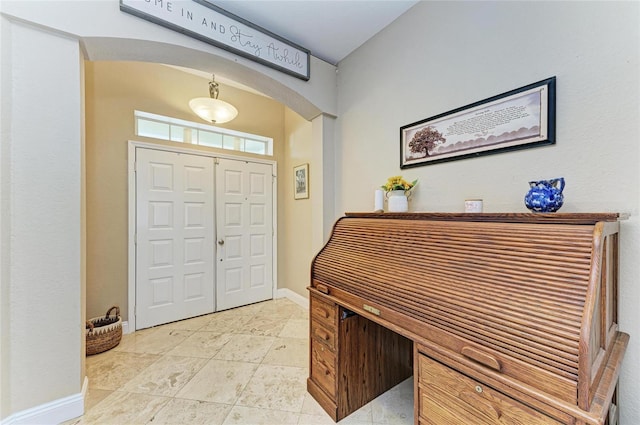 foyer with baseboards and arched walkways