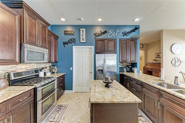 kitchen featuring light stone counters, stainless steel appliances, a kitchen island, and backsplash