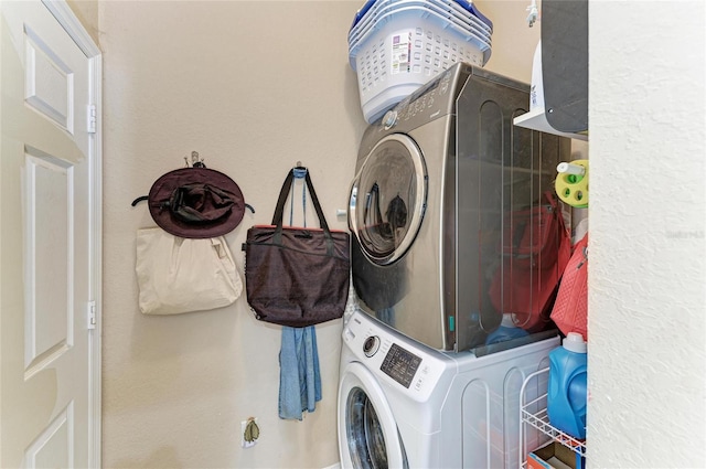 clothes washing area with stacked washer and clothes dryer and laundry area