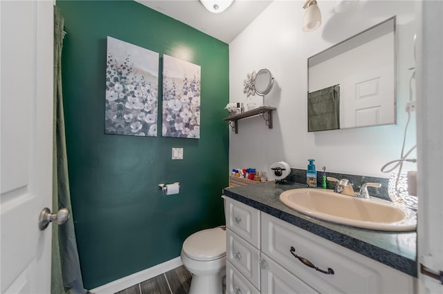 bathroom featuring vanity, toilet, wood finished floors, and baseboards