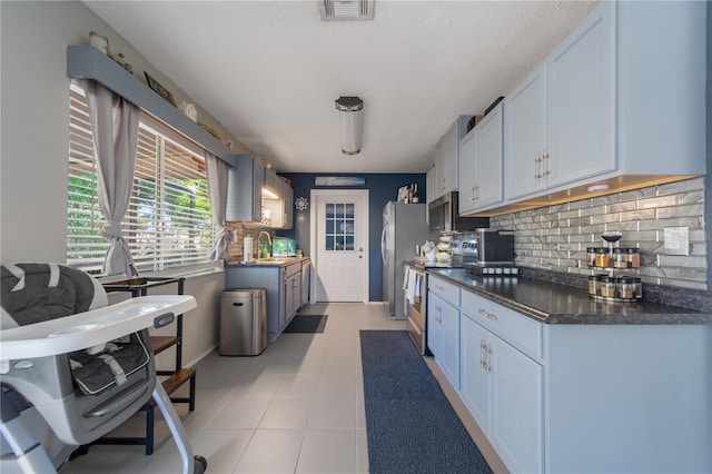 kitchen featuring visible vents, a sink, dark countertops, backsplash, and stainless steel appliances