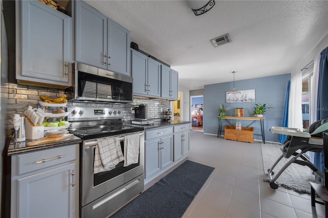 kitchen with tile patterned floors, visible vents, dark countertops, appliances with stainless steel finishes, and decorative backsplash