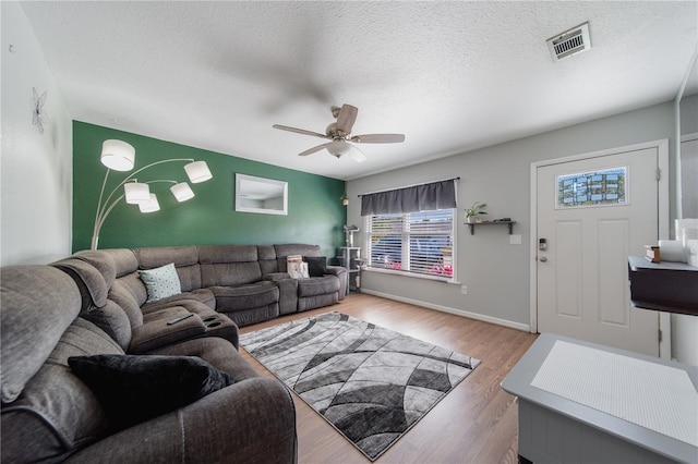 living room with ceiling fan, visible vents, a textured ceiling, and wood finished floors