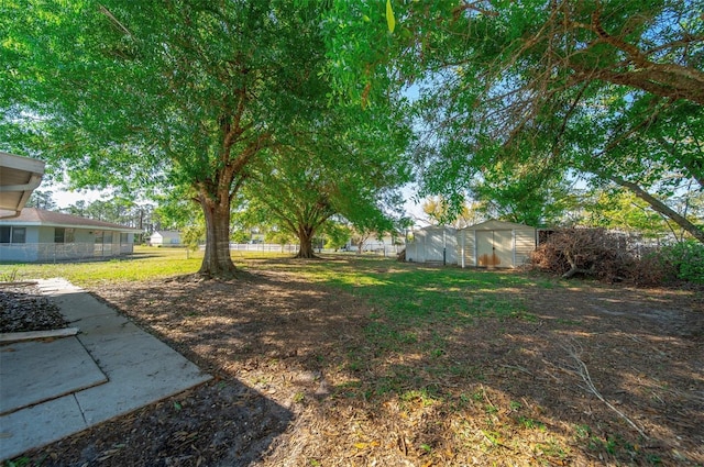 view of yard featuring a storage shed, an outdoor structure, and fence