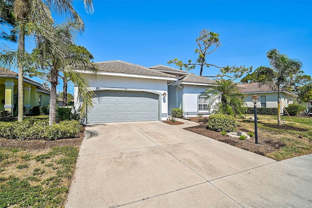 ranch-style house with concrete driveway, an attached garage, a tile roof, and stucco siding