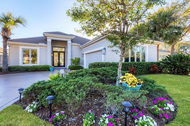 view of front of house with french doors, a garage, a front lawn, and stucco siding