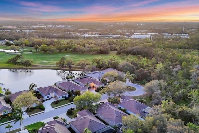 aerial view at dusk with a water view and a residential view