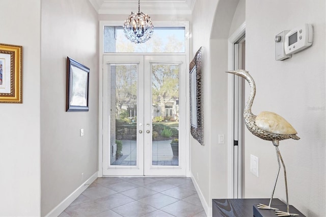 entryway with tile patterned floors, french doors, crown molding, baseboards, and a chandelier