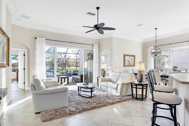 living area with visible vents, crown molding, light tile patterned floors, ceiling fan with notable chandelier, and arched walkways