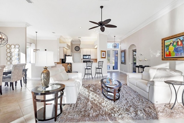 living room with arched walkways, light tile patterned floors, ceiling fan with notable chandelier, and ornamental molding