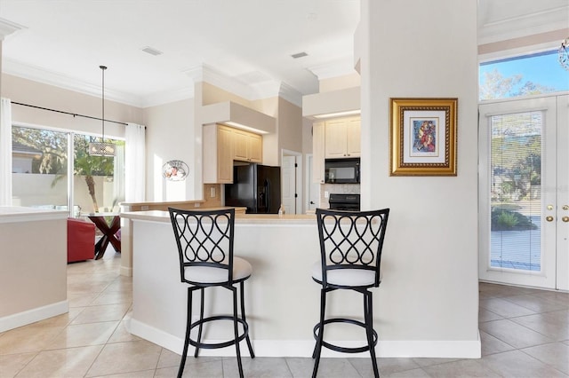 kitchen with a breakfast bar area, light tile patterned flooring, ornamental molding, black appliances, and backsplash