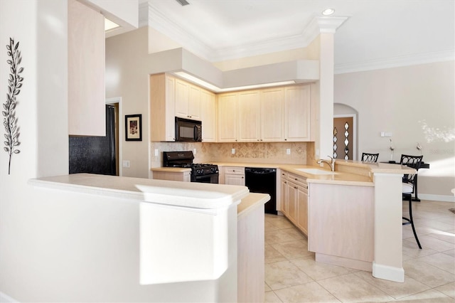 kitchen with a peninsula, arched walkways, a sink, black appliances, and a kitchen bar