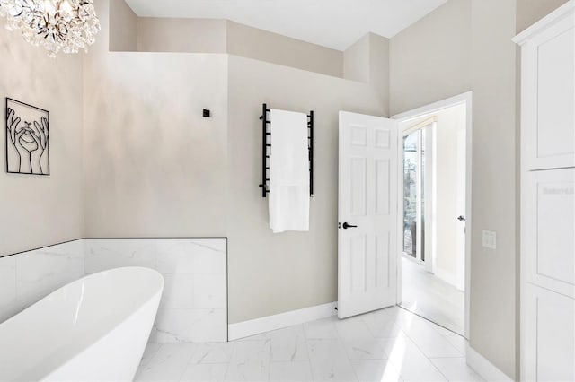 bathroom with a notable chandelier, baseboards, marble finish floor, and a freestanding bath