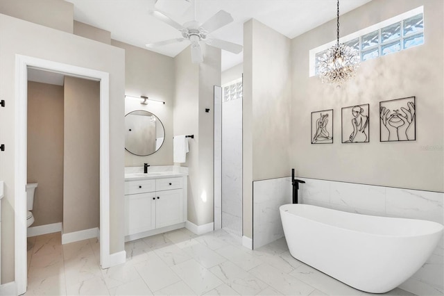 full bath with vanity, baseboards, a freestanding tub, toilet, and marble finish floor