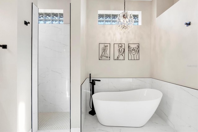 full bathroom featuring a freestanding tub, a notable chandelier, marble finish floor, and a tile shower