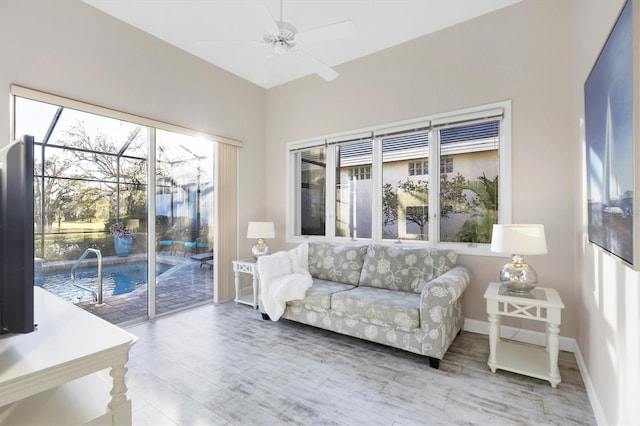 living room with ceiling fan, a sunroom, baseboards, and wood finished floors