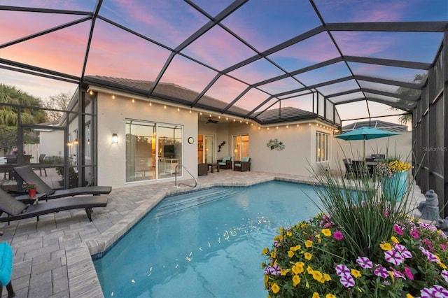 pool at dusk with glass enclosure, a patio, an outdoor living space, an outdoor pool, and ceiling fan