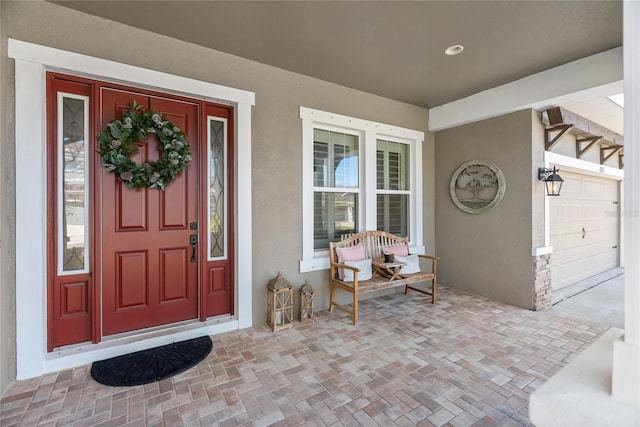 view of exterior entry with stucco siding and a porch