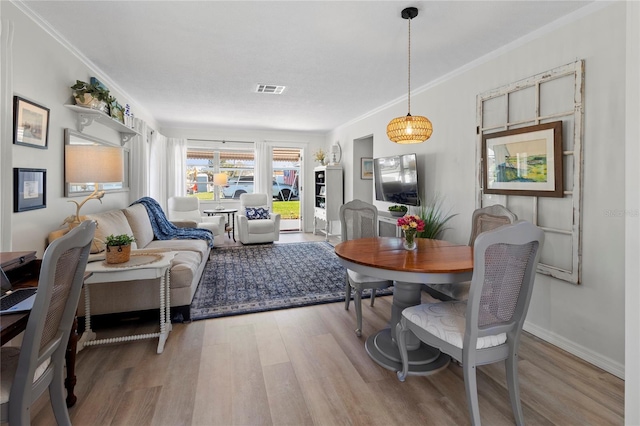 dining space with baseboards, light wood-style floors, visible vents, and ornamental molding