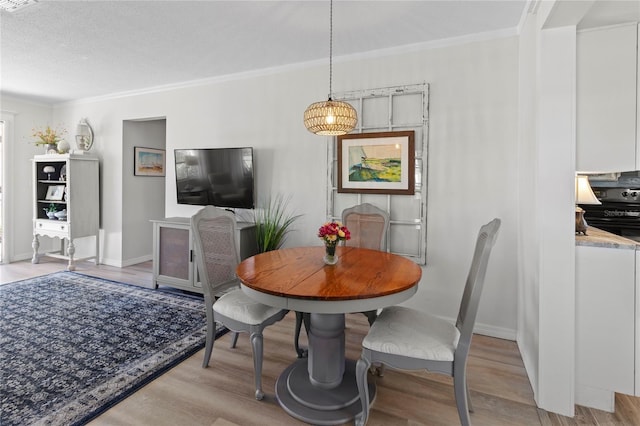 dining area featuring baseboards, light wood-style floors, and crown molding