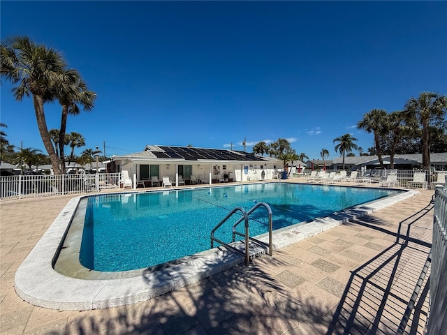 community pool with a patio and fence