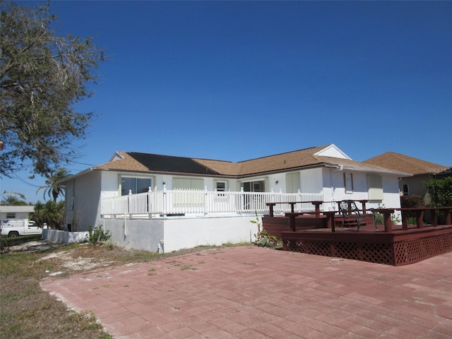 view of front of house with stucco siding, a patio, and a deck