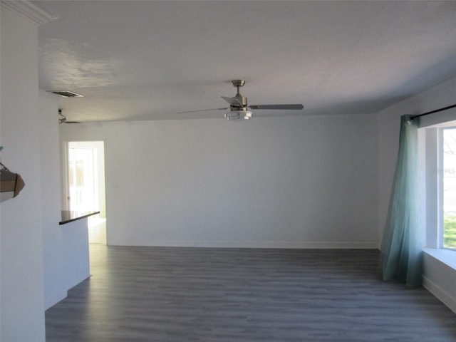 unfurnished room with visible vents, baseboards, dark wood-type flooring, and a ceiling fan