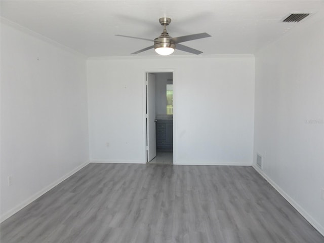 empty room featuring crown molding, wood finished floors, and visible vents