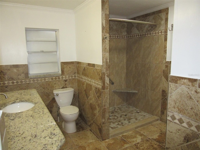 full bath featuring crown molding, toilet, vanity, tiled shower, and tile walls