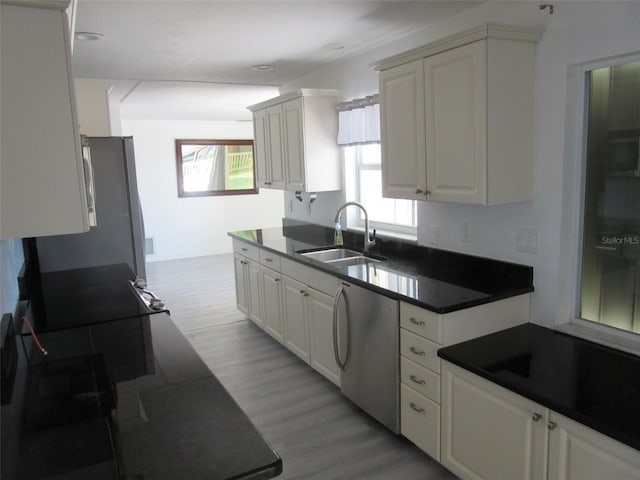 kitchen featuring a sink, light wood-style floors, dark countertops, and dishwashing machine