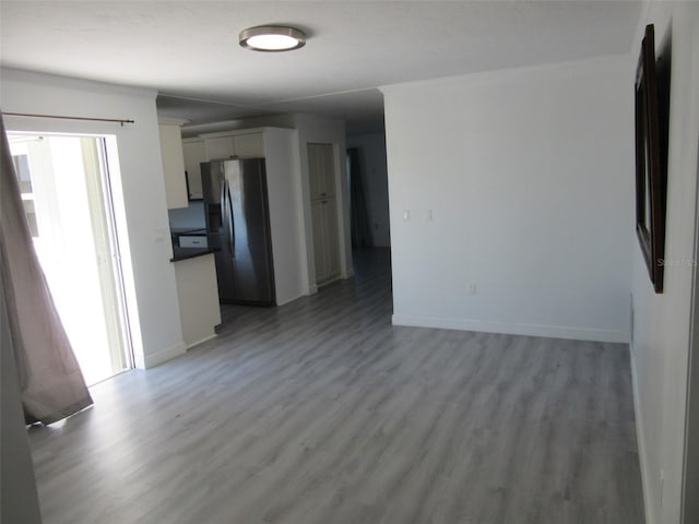 spare room featuring crown molding, light wood-style flooring, and baseboards