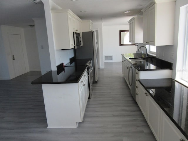 kitchen featuring white cabinetry, stainless steel appliances, light wood-type flooring, and a sink